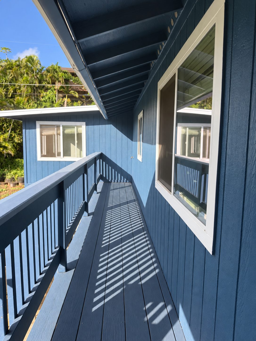 New upper-level deck walkway and railing on a blue-painted home, freshly finished