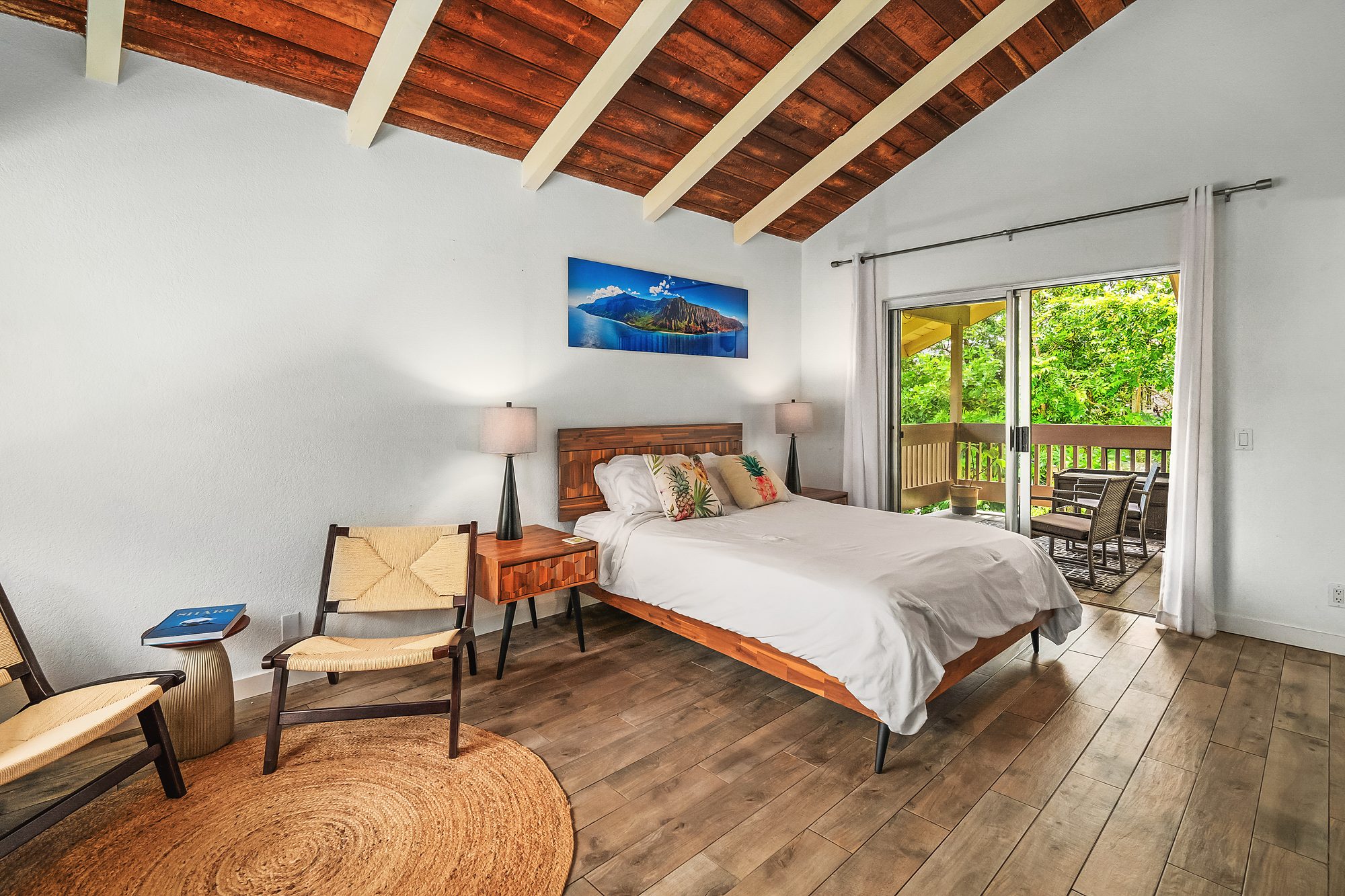 Bedroom under a wood ceiling with white beams, a wood bed and sliding doors to the lanai