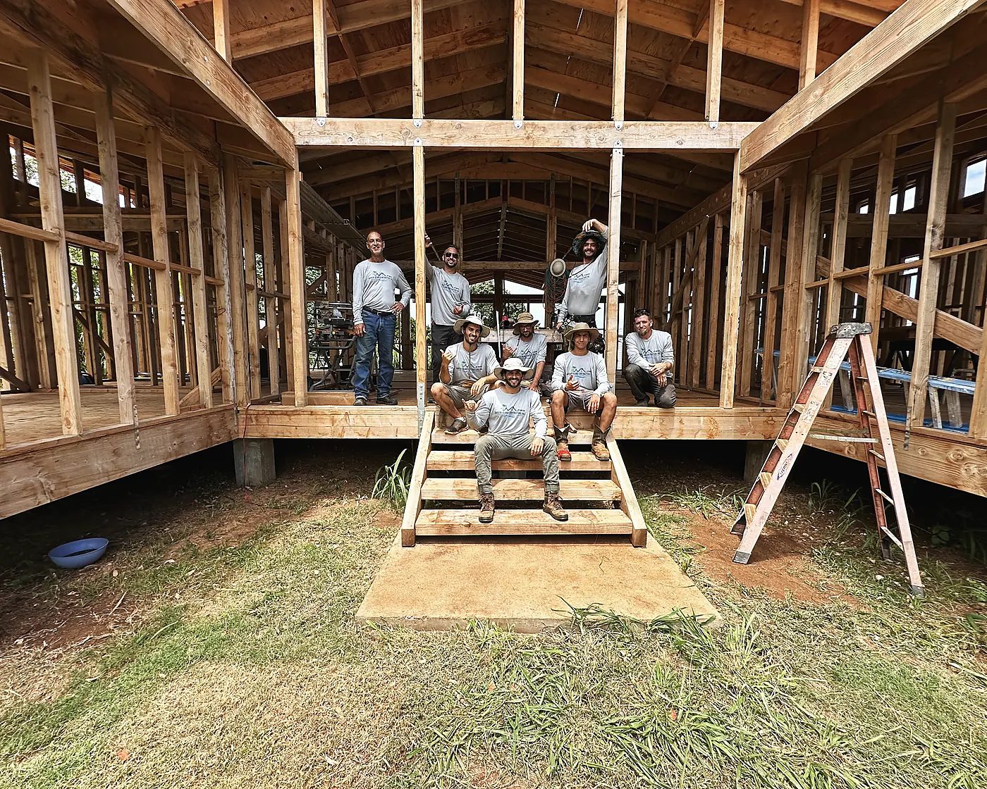Eight members of the crew sitting on the entry steps inside the framed Kapa‘a home