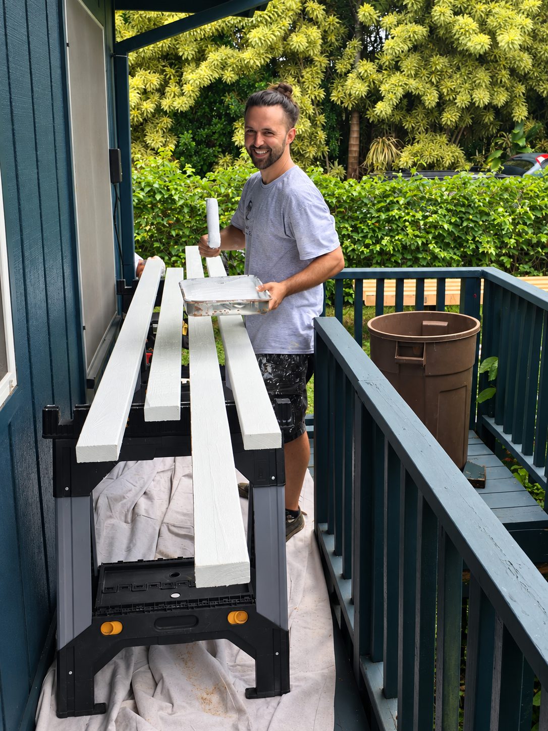 A crew member painting new railing sections on a lanai during a deck and railing replacement