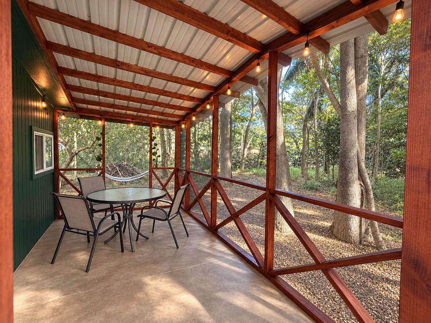 Covered lanai with red-painted posts and rafters, bamboo screening and a table