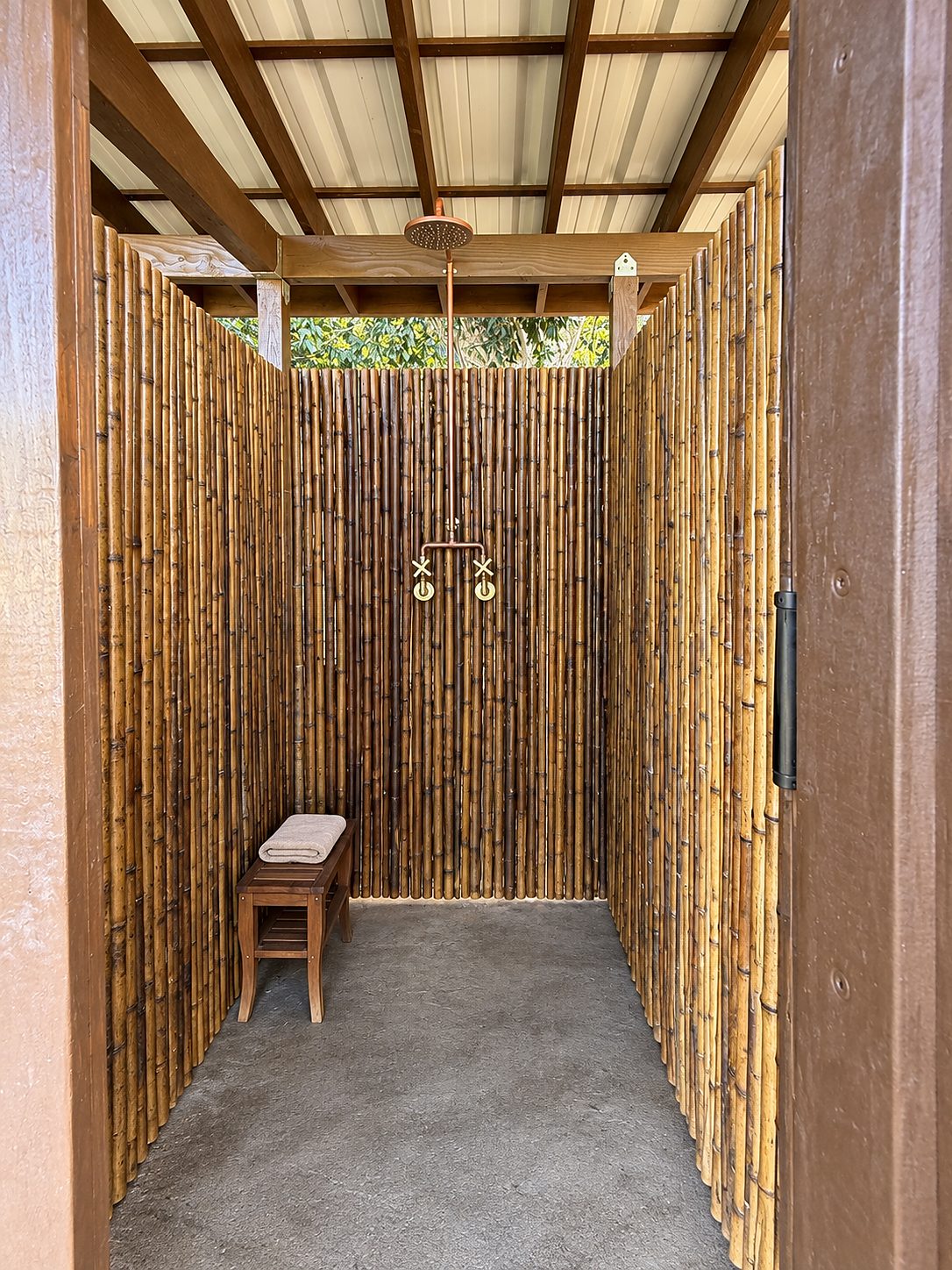 Outdoor shower with bamboo walls, a wood door and a translucent roof