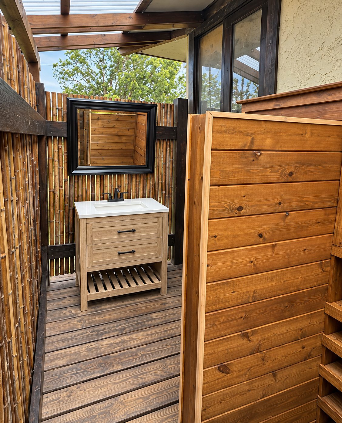 Outdoor vanity with a wood cabinet and mirror against bamboo screening