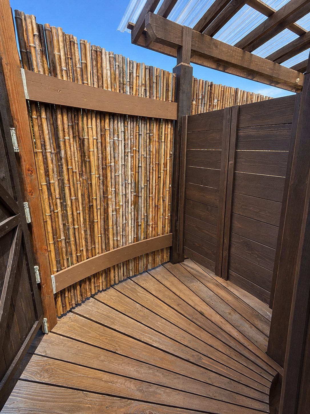 Wood-decked walkway between bamboo screens under an open roof