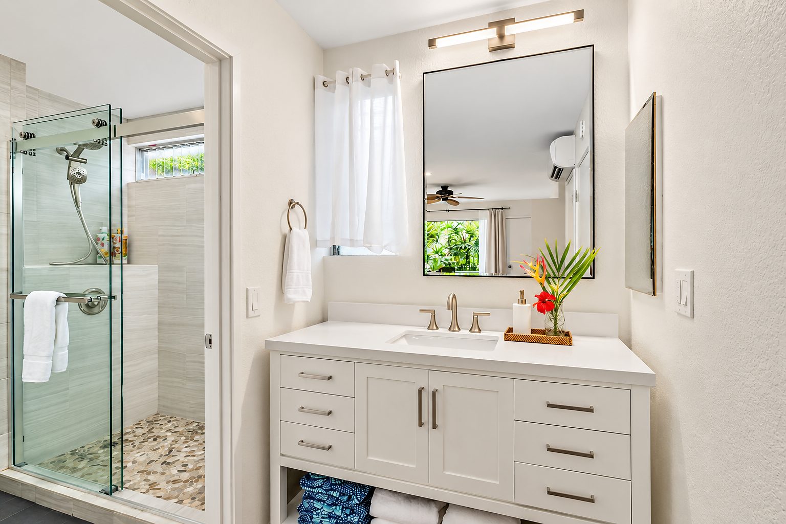 Bath with a glass shower, white vanity and a framed mirror