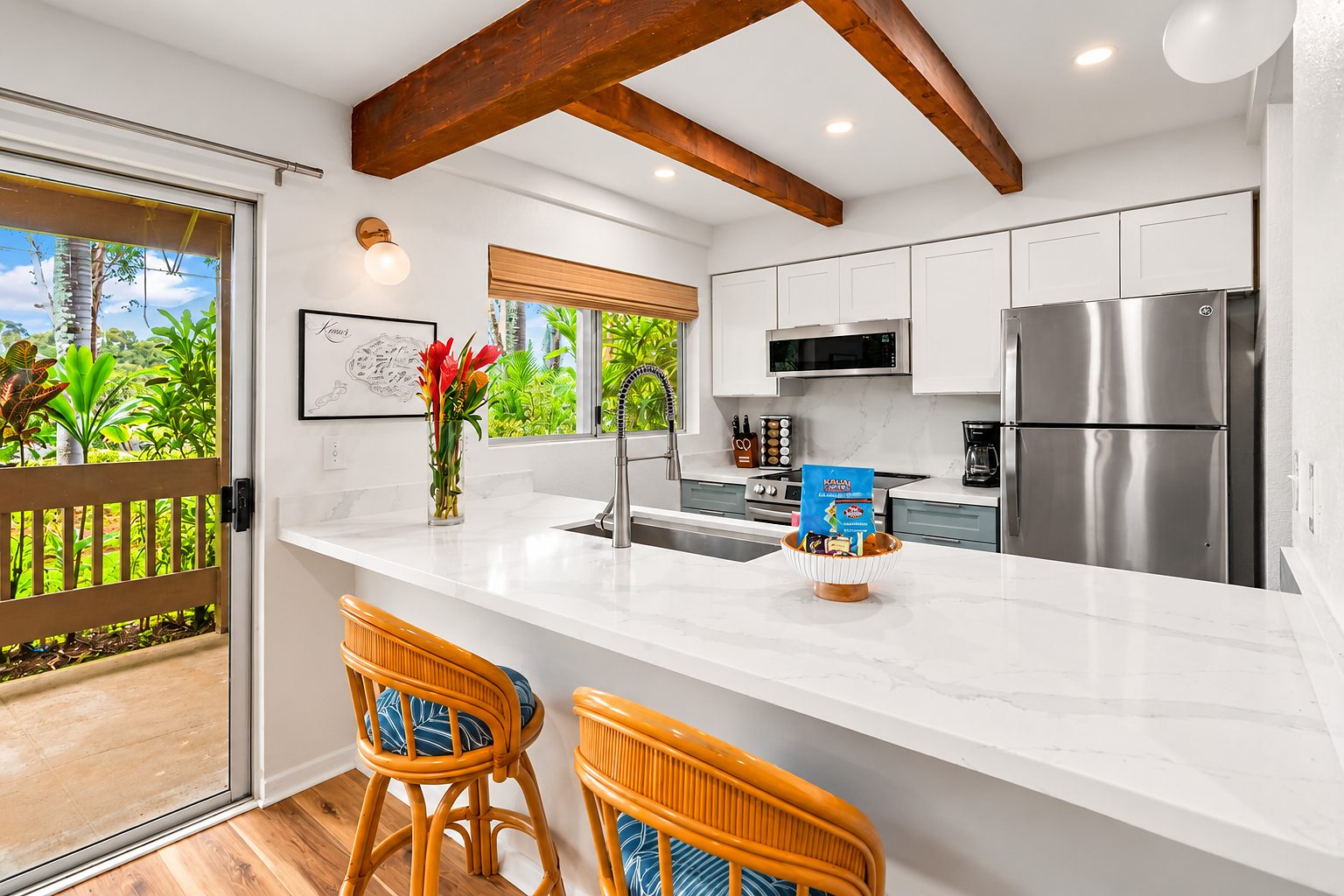Kitchen with exposed beams, white upper cabinets and red flowers in the window