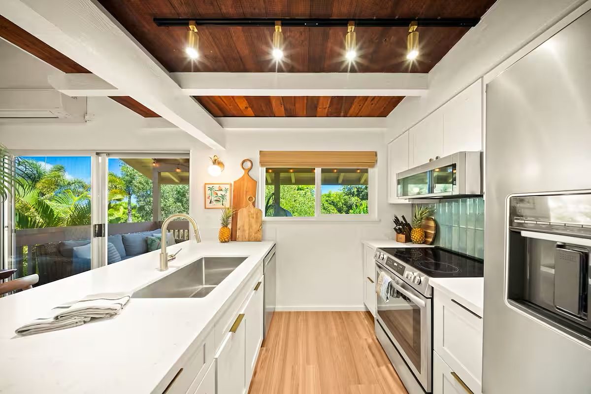 Kitchen under the wood ceiling with white cabinetry and a teal tile splashback